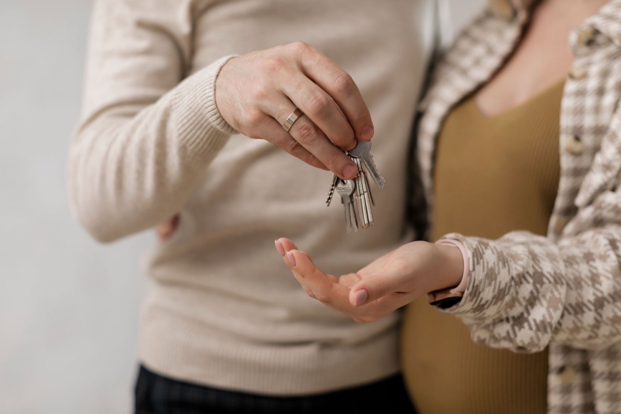 Ein Paar übergibt sich den Schlüssel zum neuen Zuhause, die Frau ist schwanger